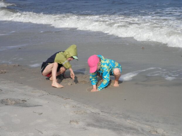Kinder spielen am Ostseestrand nahe der Wasserkante